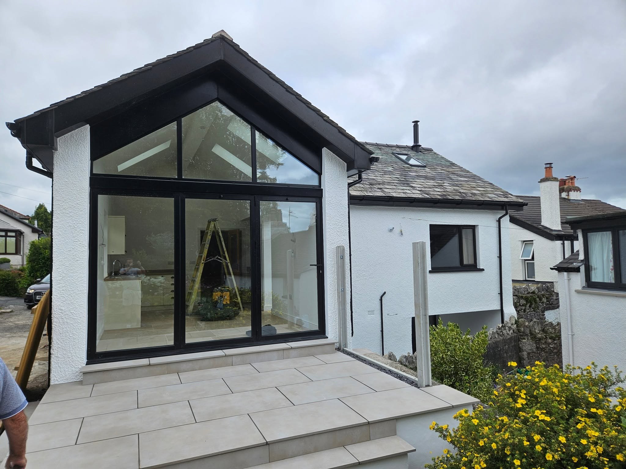 White-rendered house with a modern glazed gable extension and a slate patio
