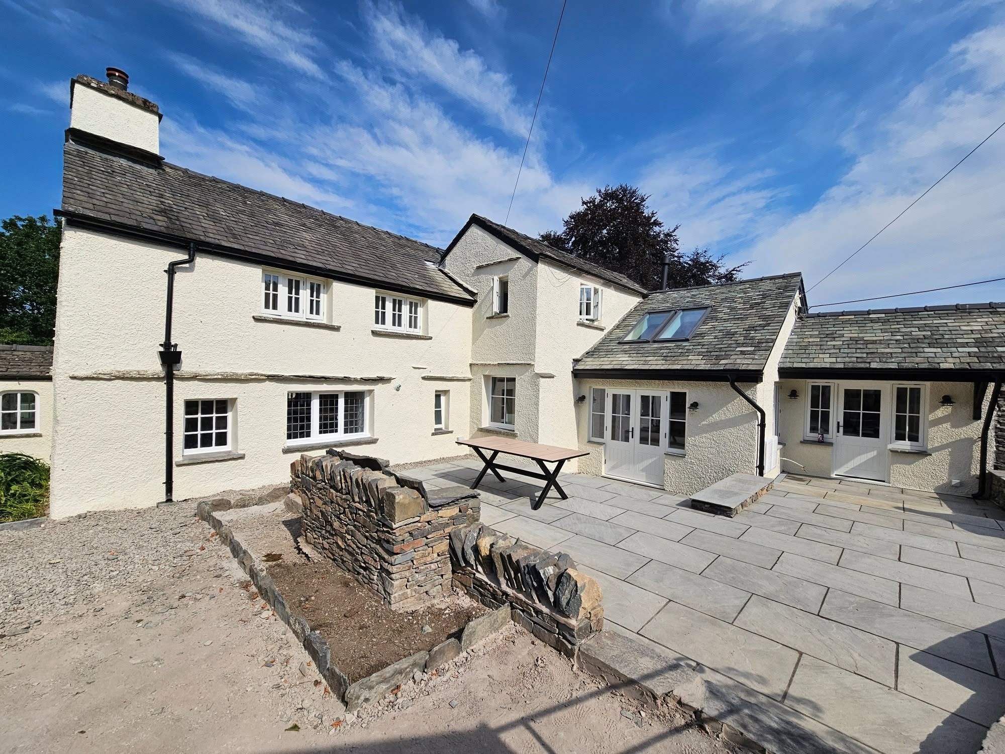 Whitewashed cottage with slate roofs and a flagged courtyard