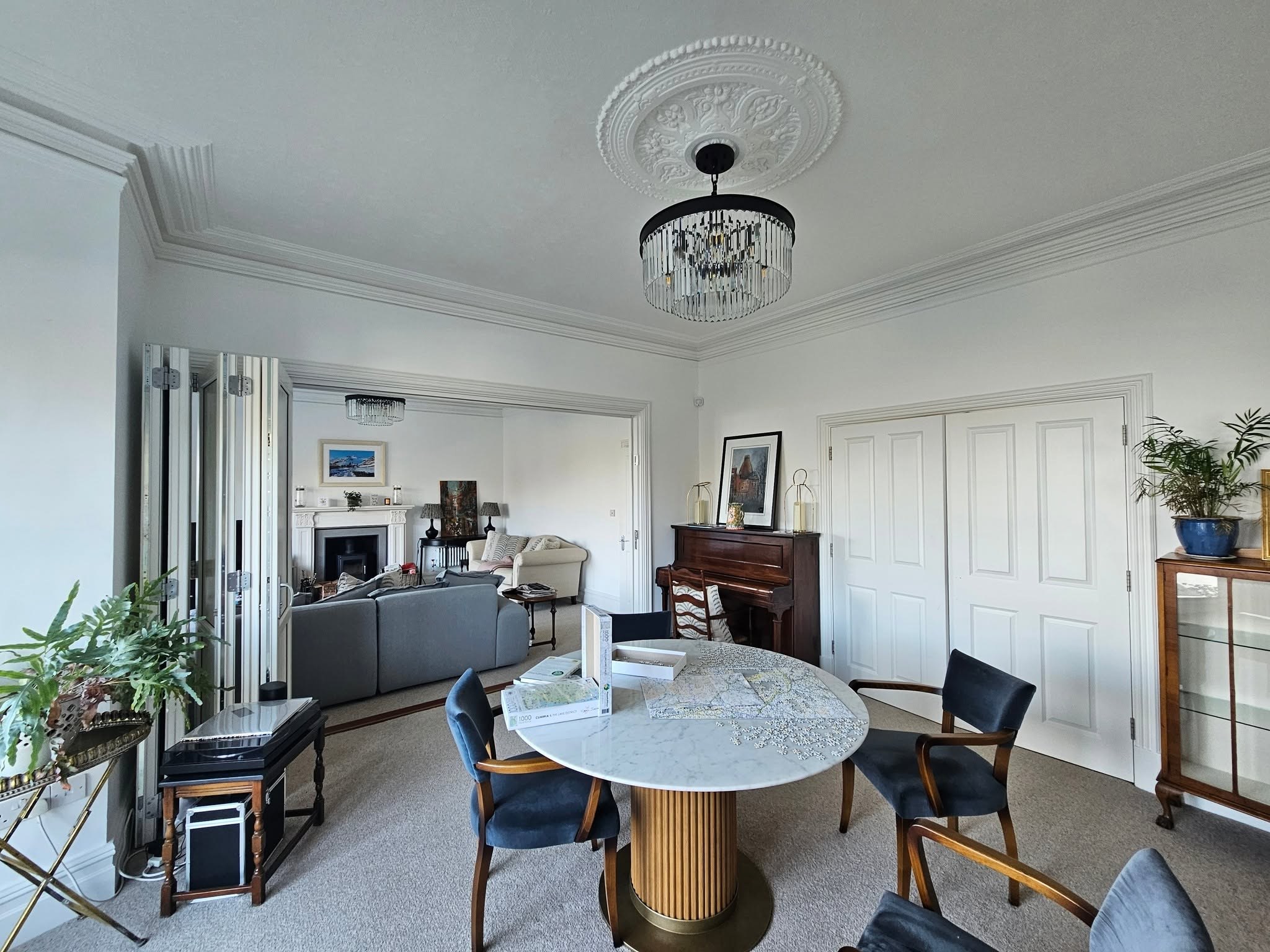 Lounge and dining room with a ceiling rose, chandelier and panelled doors