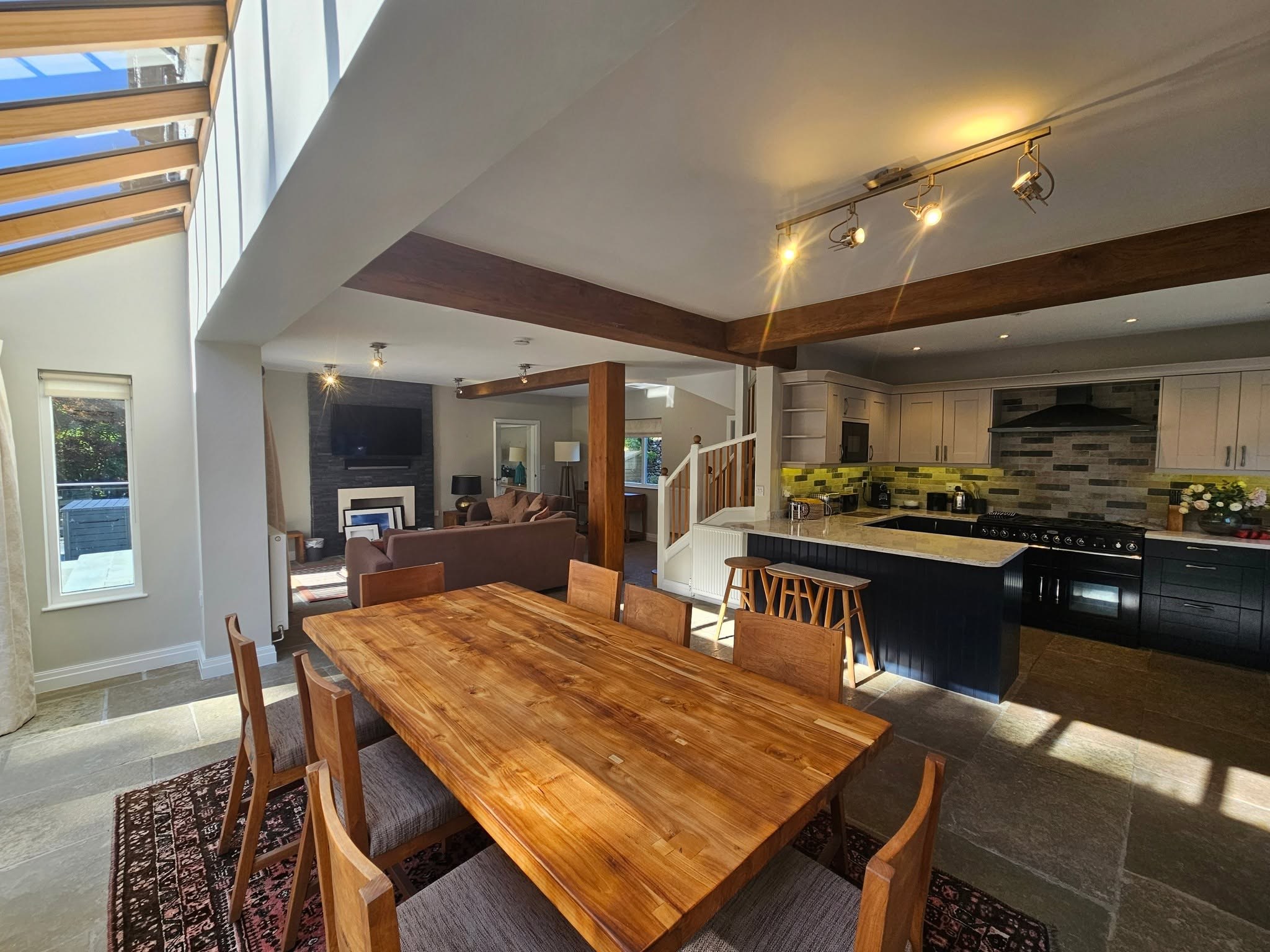 Open-plan kitchen-diner with an oak table, beams and roof light