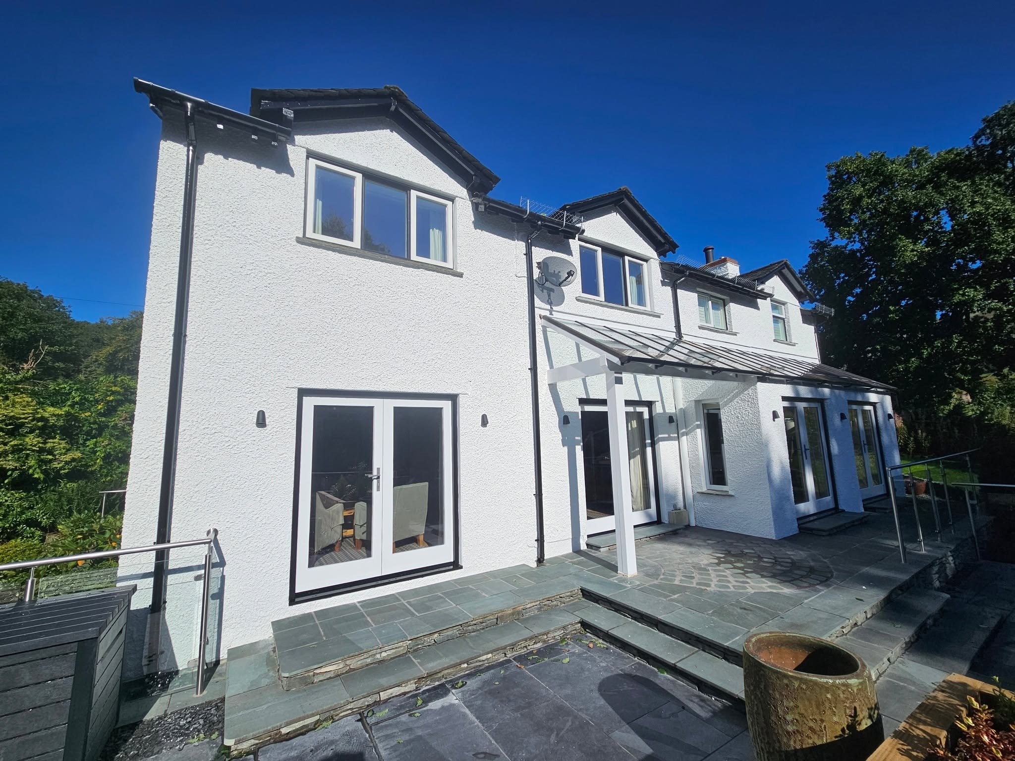 Freshly painted white house with a slate terrace and glass balustrade