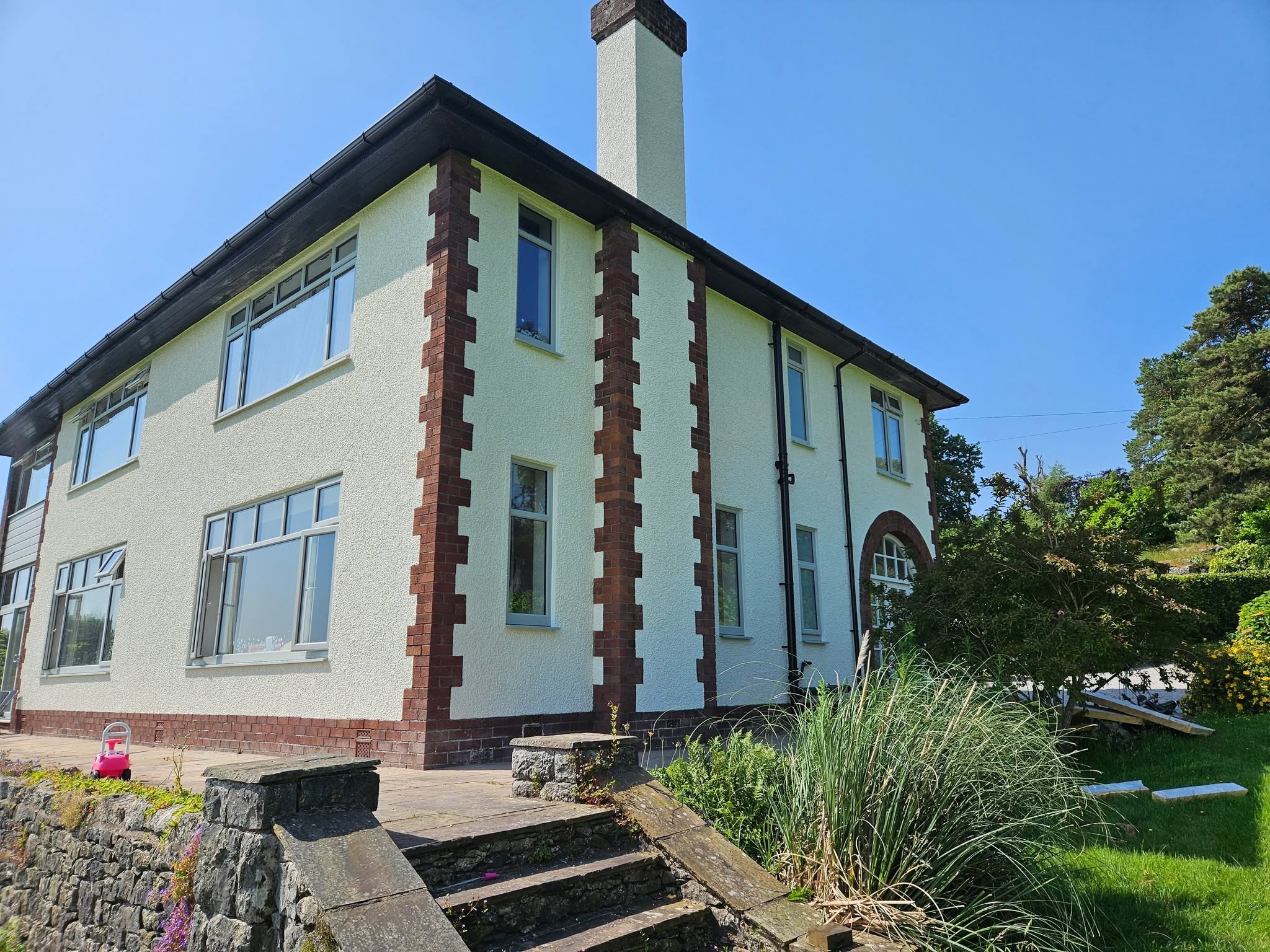 Pale rendered house with red sandstone quoins and stone steps