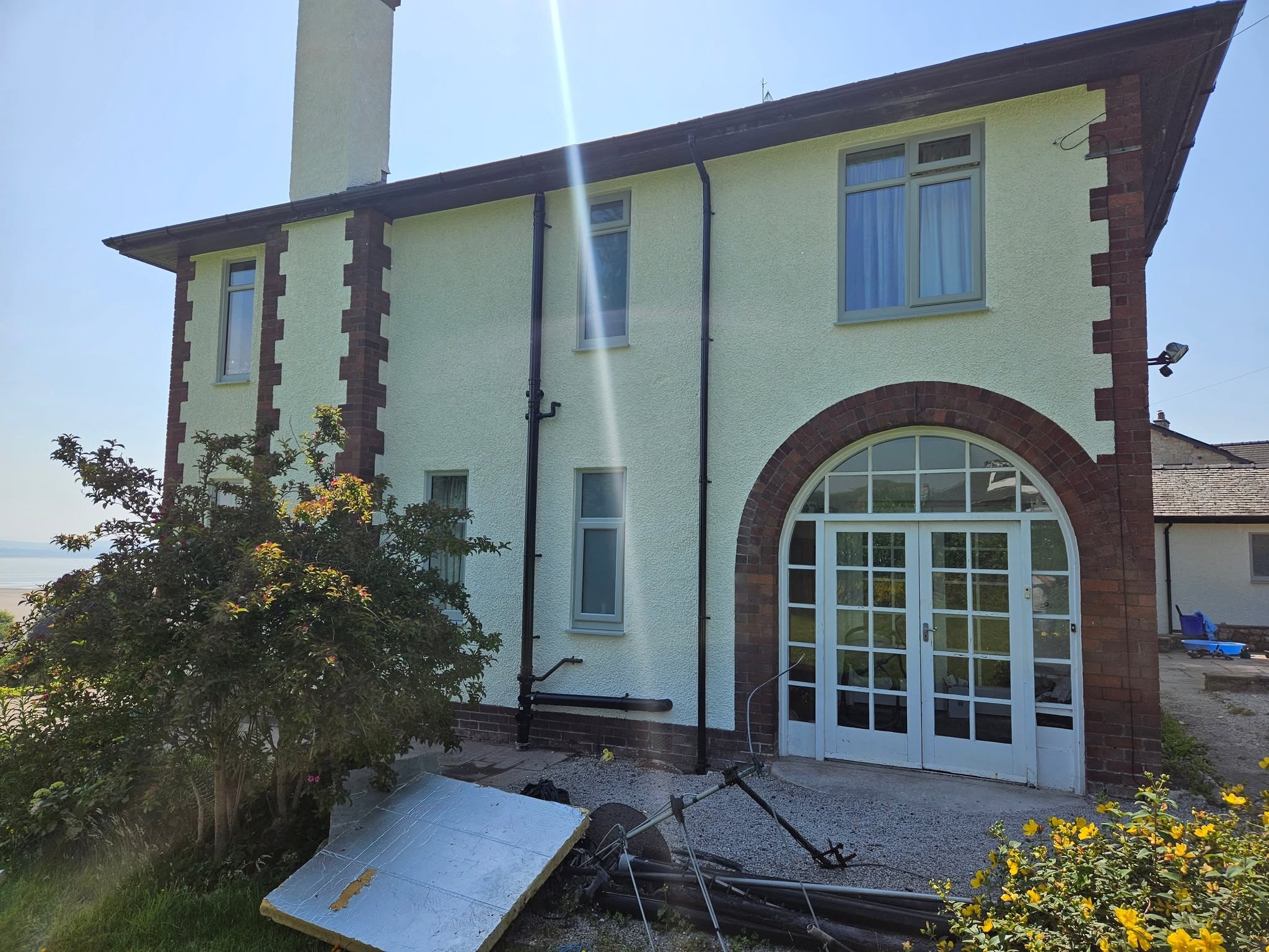 Arched French doors framed in red sandstone on a freshly painted house