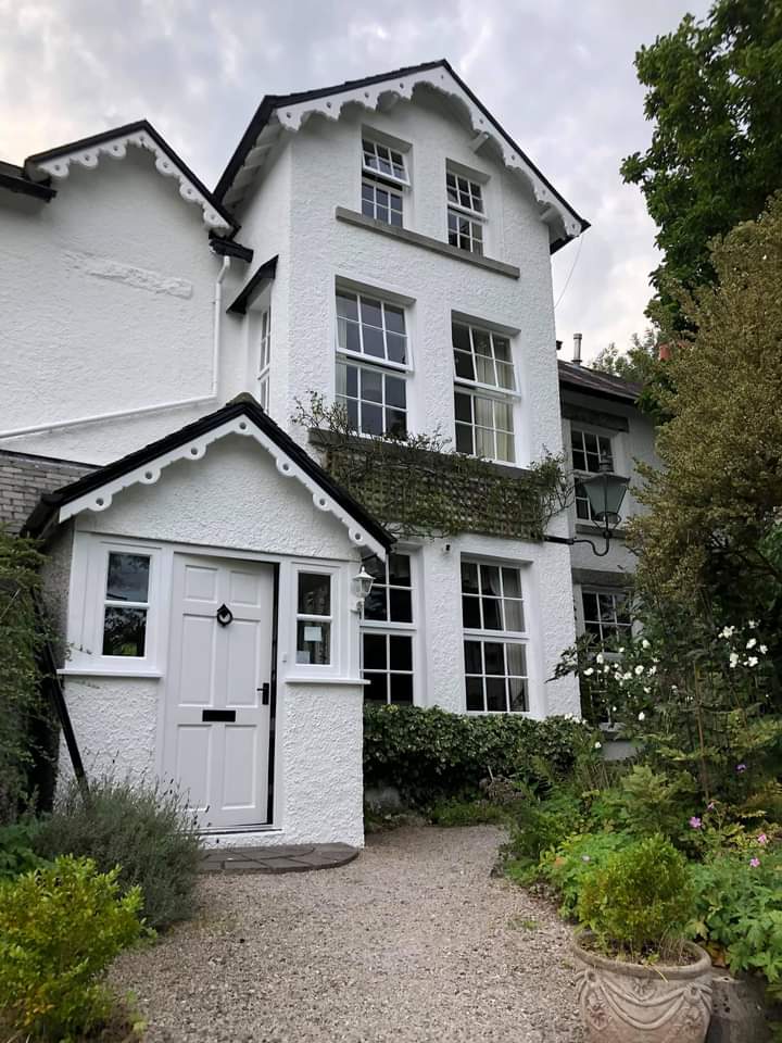Tall white Victorian house with decorative bargeboards and a pale grey front door