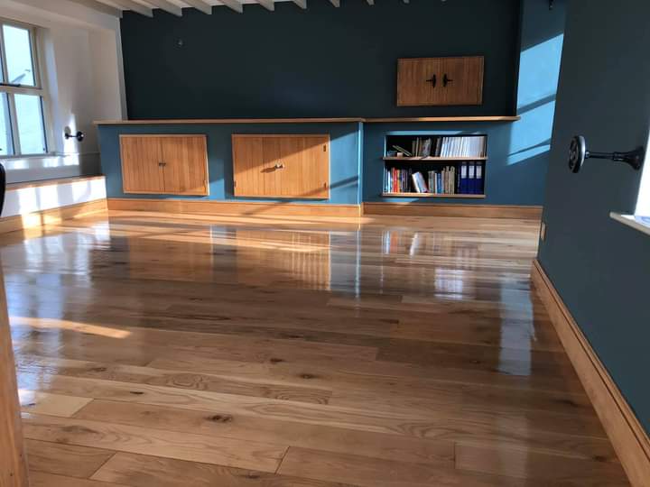 Room with a deep teal feature wall, oak cupboards and oak floor