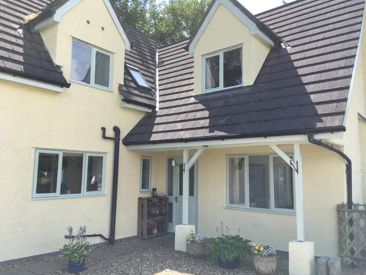 Cream rendered house with dormer windows and a white-trimmed porch